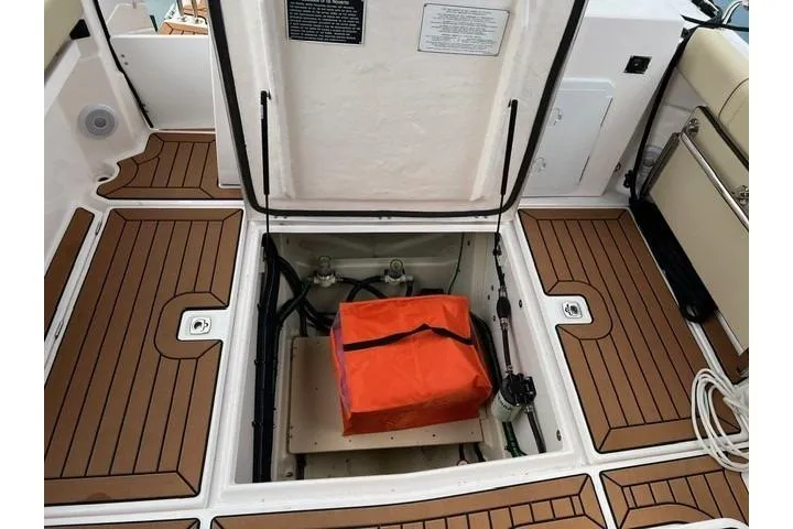 Slide: The Image of 2025 Ranger Tugs R-25 Luxury Edition boat storage compartment with orange bag, teak flooring. - 9