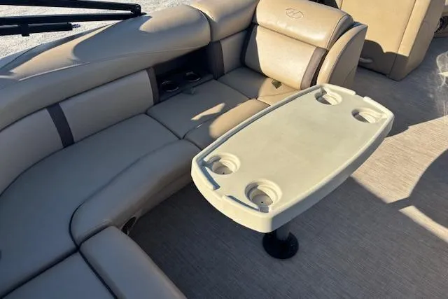 Slide: The Image of 2020 Harris Cruiser 210 boat interior with beige seating and a table with cup holders. - 17