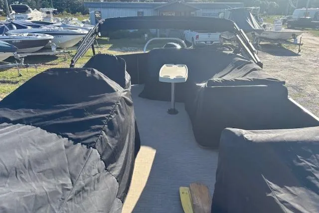 Slide: The Image of 2020 Harris Cruiser 210 pontoon boat with covered seating, parked outdoors. - 25