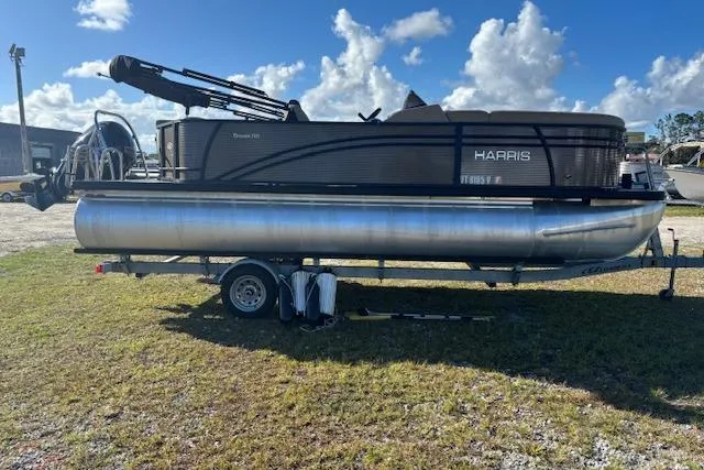Slide: The Image of 2020 Harris Cruiser 210 pontoon boat on trailer under a clear blue sky. - 5