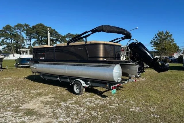 Slide: The Image of 2020 Harris Cruiser 210 pontoon boat on trailer, parked on grass under clear blue sky. - 7