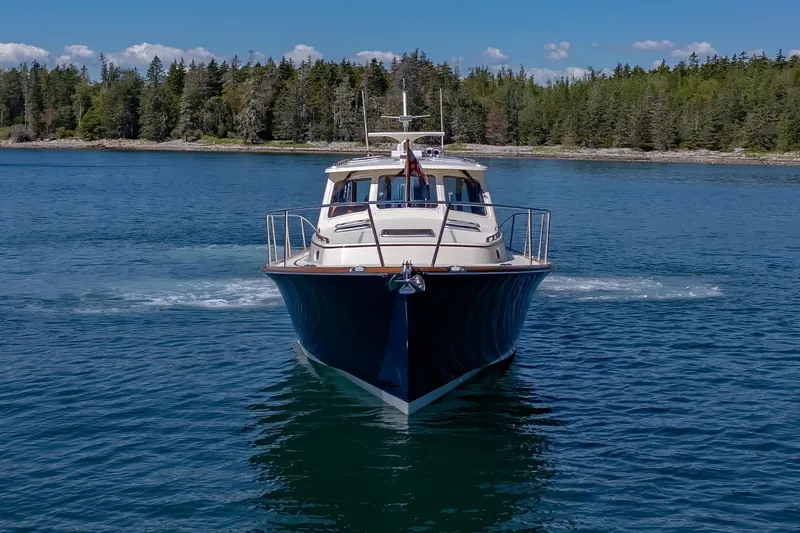 Slide: The Image of 2009 Hinckley Talaria 44 MY yacht cruising on a serene lake with forested shoreline. - 2