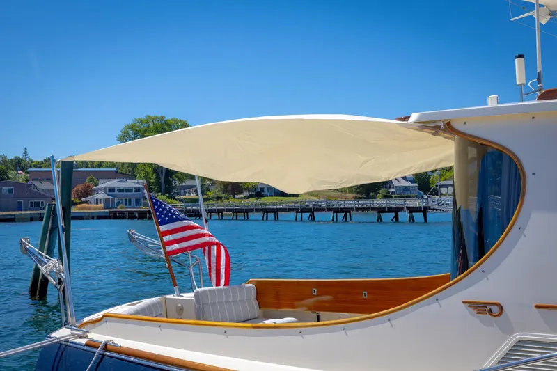 Slide: The Image of 2009 Hinckley Talaria 44 MY yacht with American flag, docked by waterfront homes. - 20