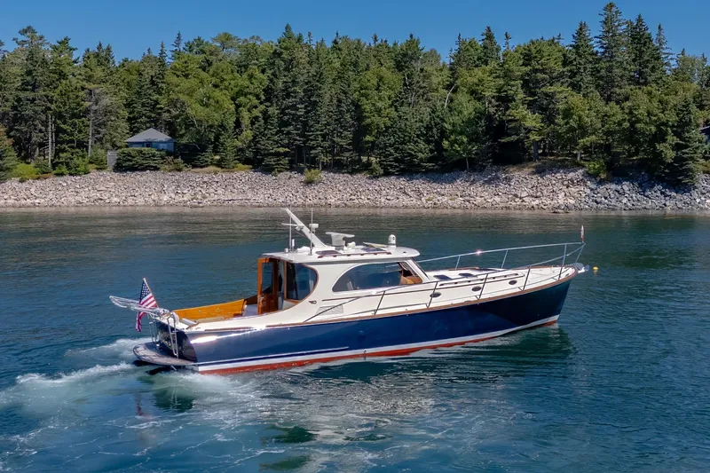 Slide: The Image of 2009 Hinckley Talaria 44 MY yacht cruising on a scenic lake with forested shoreline. - 6