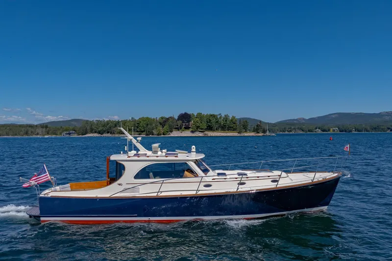 Slide: The Image of 2009 Hinckley Talaria 44 MY cruising on a scenic lake under a clear blue sky. - 9