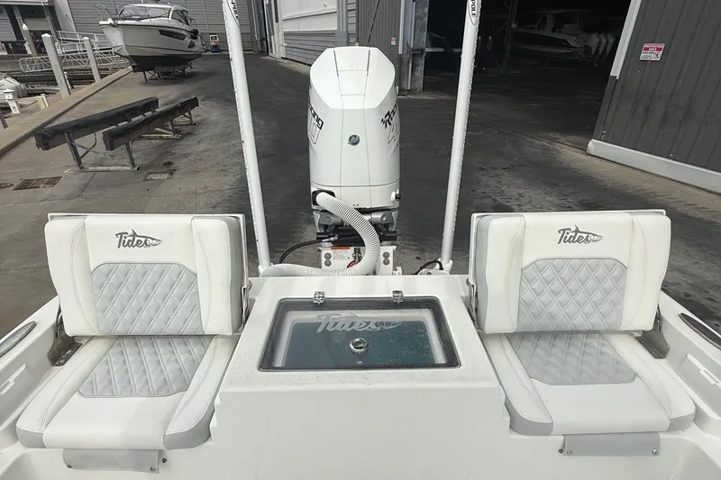 Slide: The Image of 2023 Tides 26 boat interior with dual seats and motor at a marina. - 15