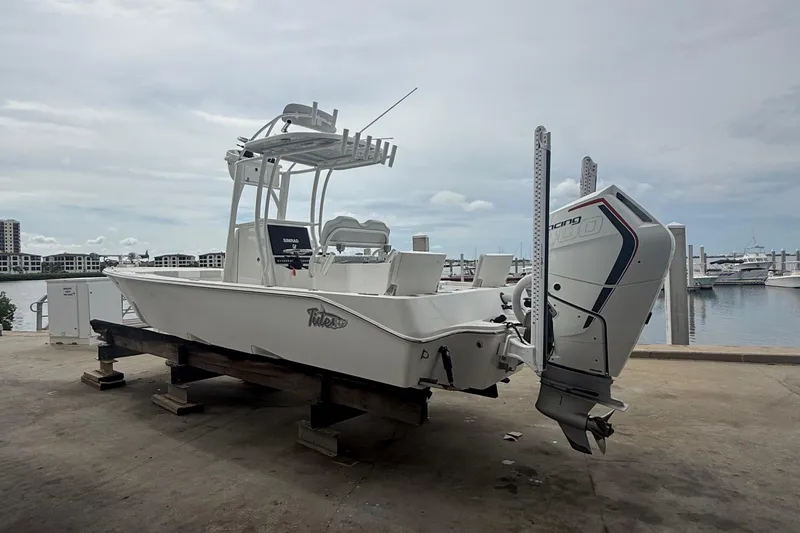 Slide: The Image of 2023 Tides 26 boat with outboard motor on dock, marina background. - 2