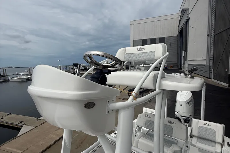Slide: The Image of 2023 Tides 26 boat helm with steering wheel, docked near industrial buildings. - 22