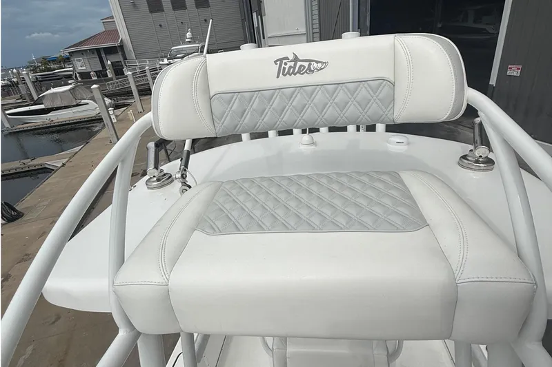 Slide: The Image of White leather seat on 2023 Tides 26 boat, featuring diamond stitching and marina background. - 23