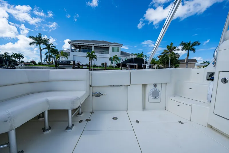 Slide: The Image of 2014 SeaVee 430 boat interior with white seating, docked near a waterfront home. - 33