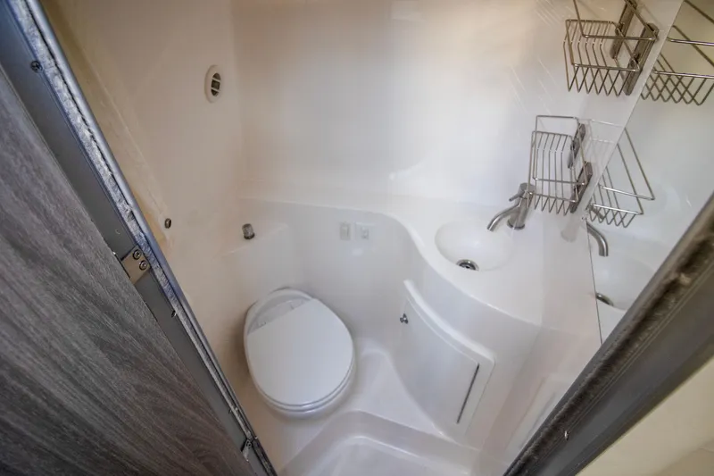 Slide: The Image of 2020 Regal 26 XO boat bathroom with toilet, sink, and storage shelves. - 5