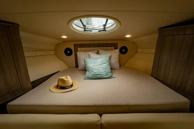 Slide: The Image of 2021 Regal 33 OBX cabin interior with cozy bed and decorative pillows. - 11