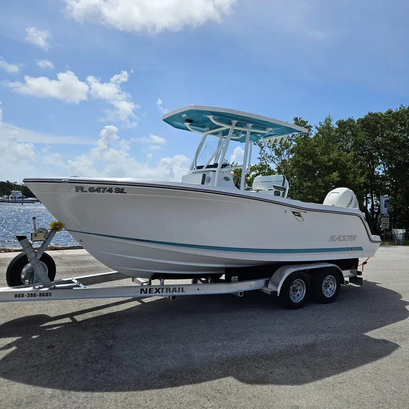 The Image of 2019 Blackfin 222 CC boat on trailer by the water, under a clear sky. - 0