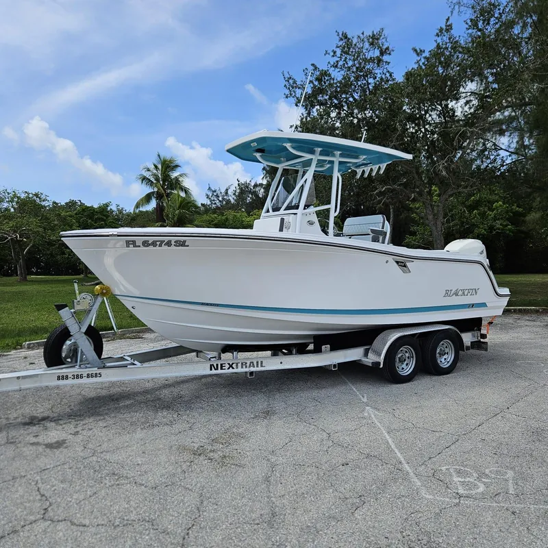 Slide: The Image of 2019 Blackfin 222 CC boat on trailer, parked outdoors with trees in the background. - 22