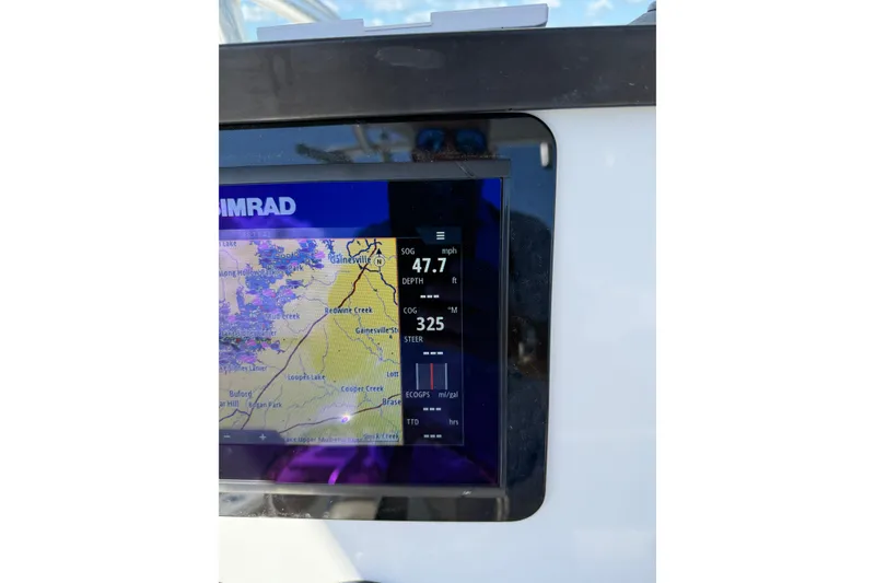 Slide: The Image of 2018 Sea Fox 248 Commander boat interior with helm and seating, near a scenic lake. - 10