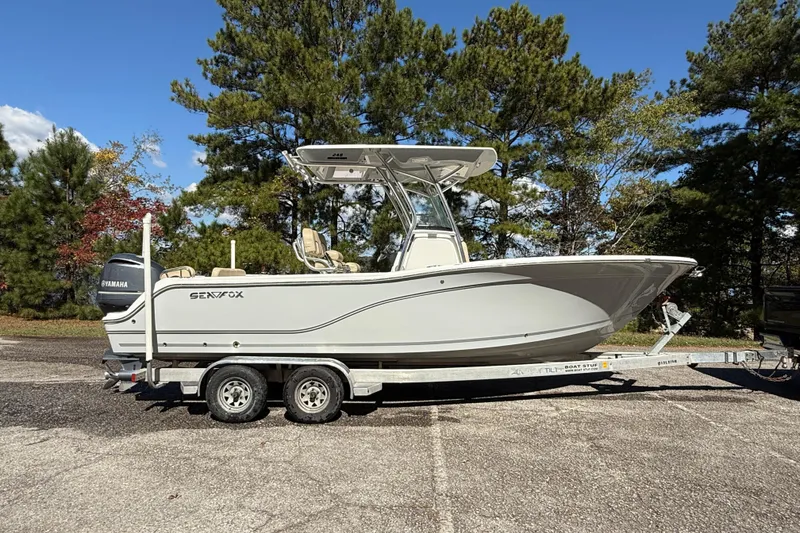 Slide: The Image of 2018 Sea Fox 248 Commander boat on trailer, parked outdoors with trees in background. - 2
