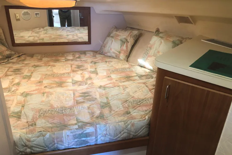 Slide: The Image of Cozy cabin interior of 1999 Mainship 31 Sedan Bridge with patterned bedding and wooden cabinetry. - 20