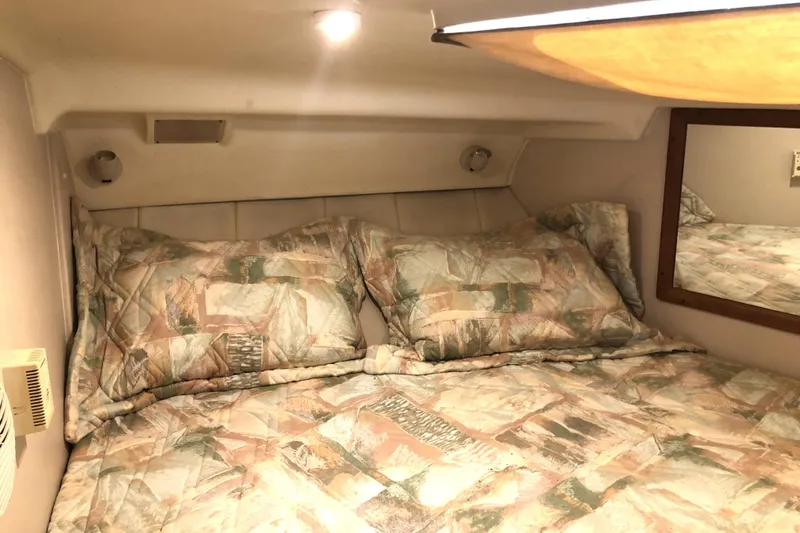 Slide: The Image of Cozy cabin interior of 1999 Mainship 31 Sedan Bridge with patterned bedding and soft lighting. - 22