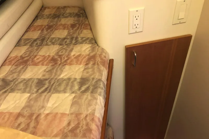 Slide: The Image of 1999 Mainship 31 Sedan Bridge cabin interior with patterned bedding and wooden cabinet. - 26