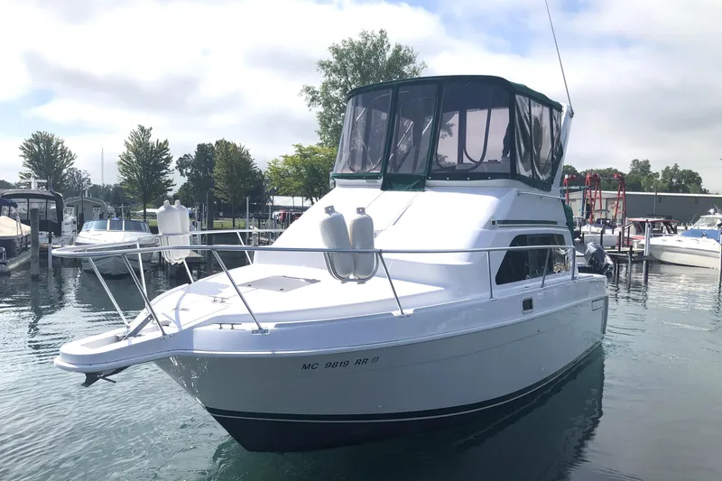 Slide: The Image of 1999 Mainship 31 Sedan Bridge yacht docked in a marina, featuring sleek design and spacious deck. - 3