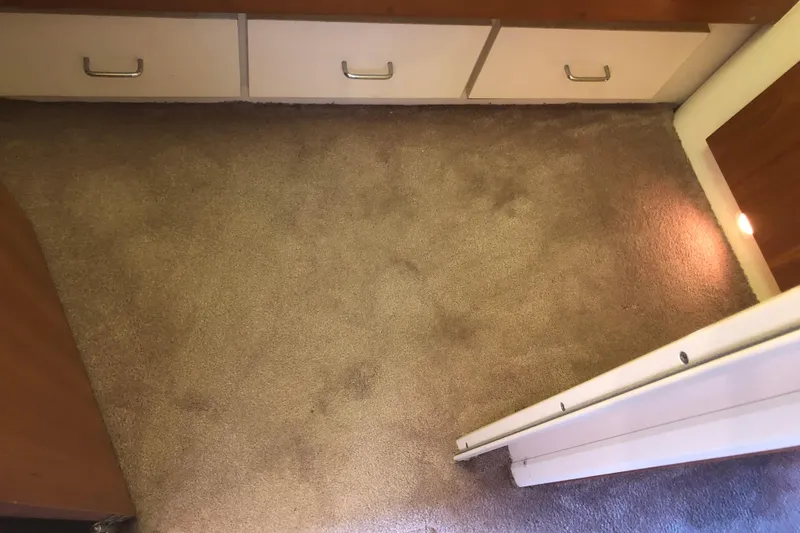 Slide: The Image of Carpeted interior of 1999 Mainship 31 Sedan Bridge with storage drawers. - 30