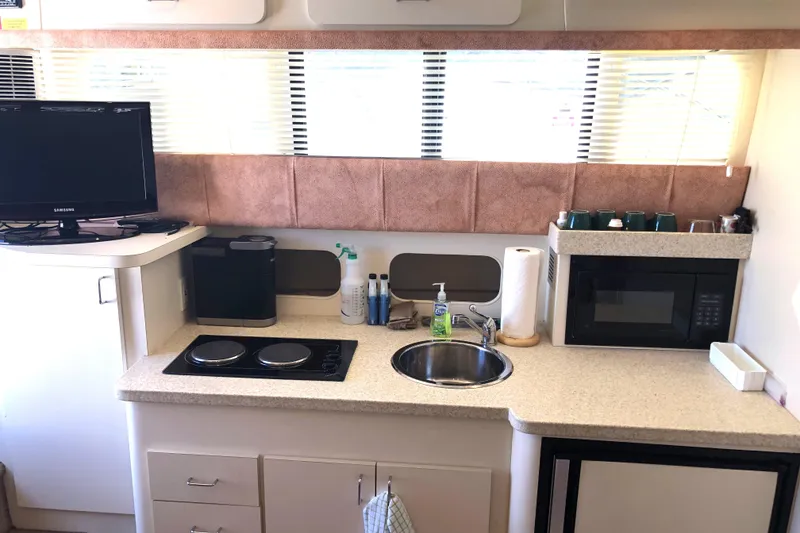 Slide: The Image of 1999 Mainship 31 Sedan Bridge kitchen with stove, sink, microwave, and TV. - 31