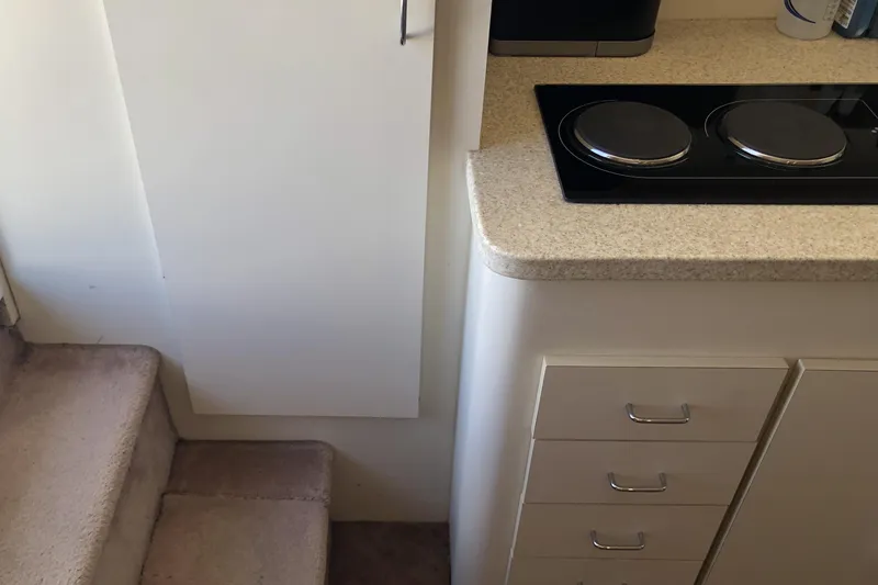 Slide: The Image of Interior of 1999 Mainship 31 Sedan Bridge with stairs, cabinets, and stovetop. - 36