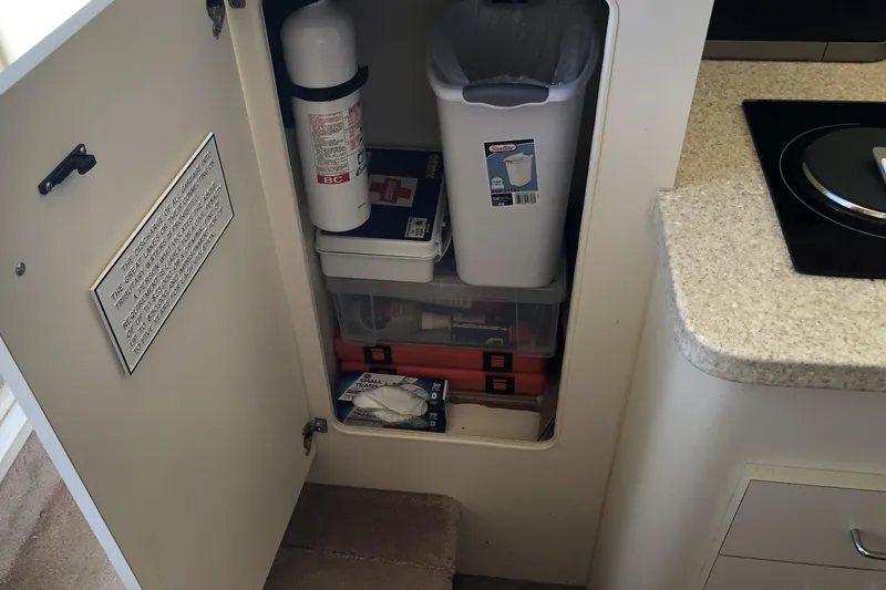 Slide: The Image of Cabinet storage on 1999 Mainship 31 Sedan Bridge with fire extinguisher and trash bin. - 39