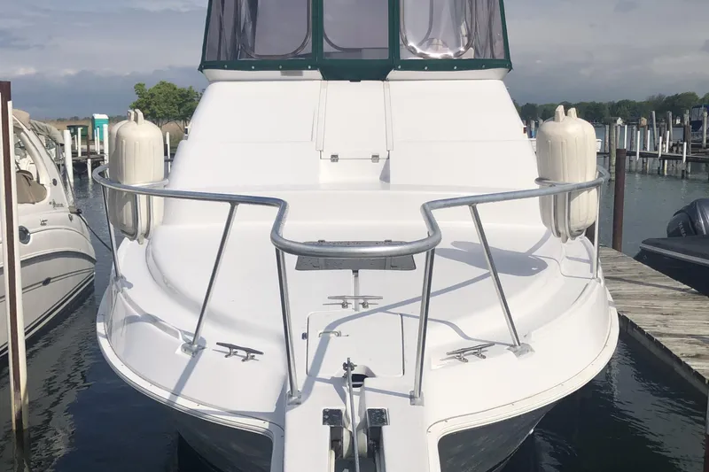Slide: The Image of 1999 Mainship 31 Sedan Bridge boat docked at marina, front view with railings and fenders. - 5