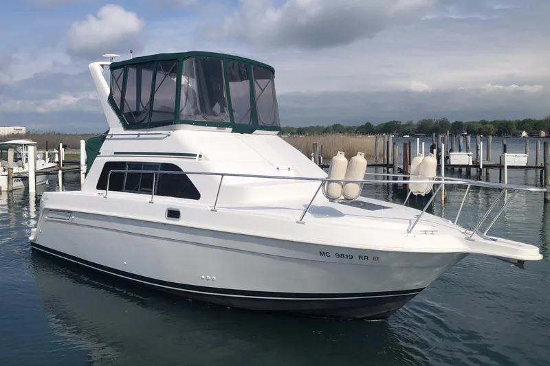 Slide: The Image of 1999 Mainship 31 Sedan Bridge yacht docked in a marina under cloudy skies. - 7