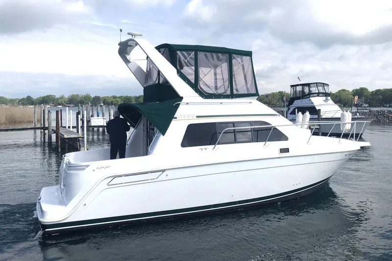 Slide: The Image of 1999 Mainship 31 Sedan Bridge boat docked on calm water under cloudy sky. - 8
