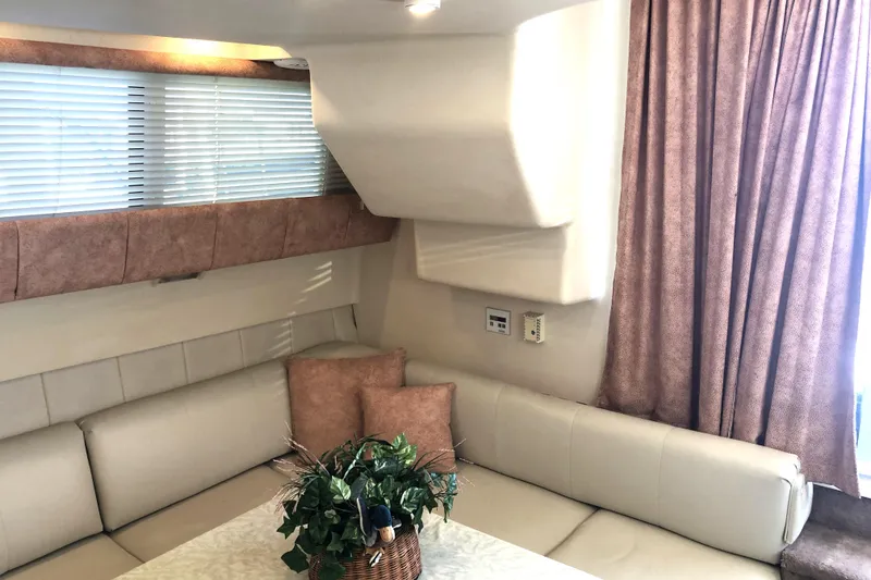Slide: The Image of 1999 Mainship 31 Sedan Bridge interior with beige seating, decorative pillows, and a potted plant. - 9