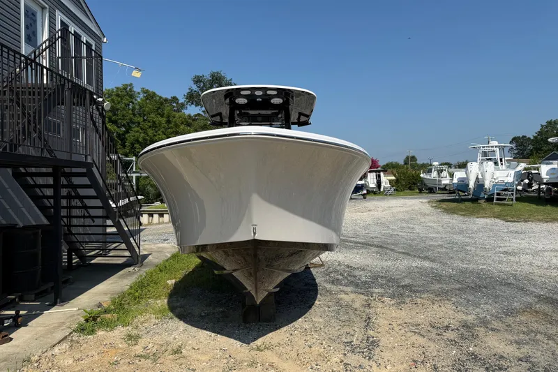Slide: The Image of 2026 Sportsman Open 232 Center Console boat on gravel near building. - 1