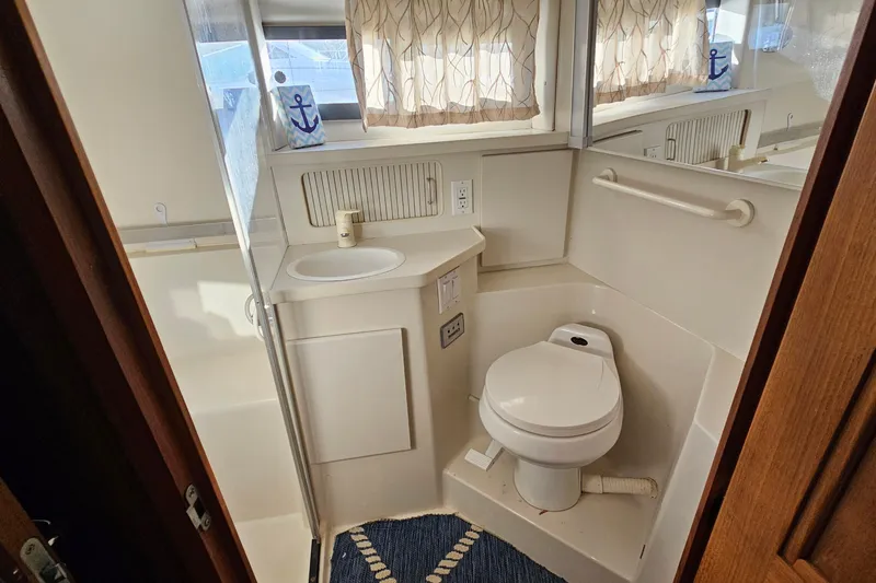 Slide: The Image of 1995 Carver 355 Aft Cabin Motor Yacht bathroom with toilet, sink, and nautical decor. - 29