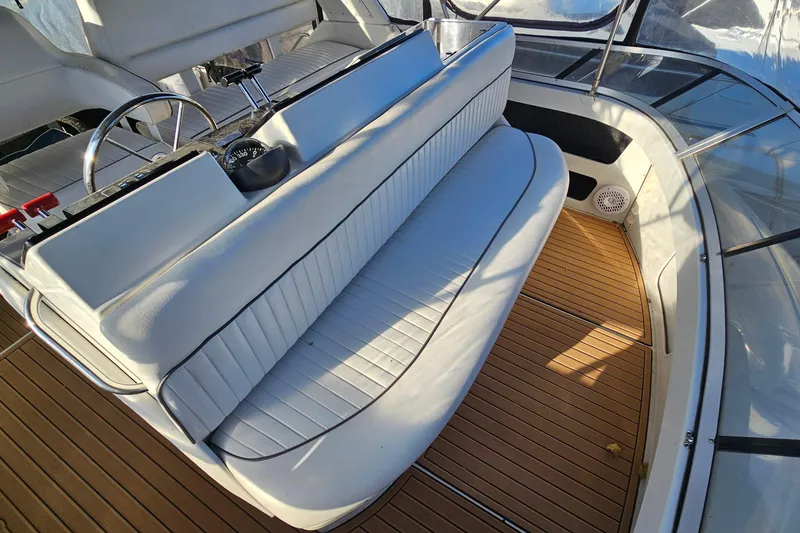 Slide: The Image of 1995 Carver 355 Aft Cabin Motor Yacht helm with white seating and wooden deck. - 11