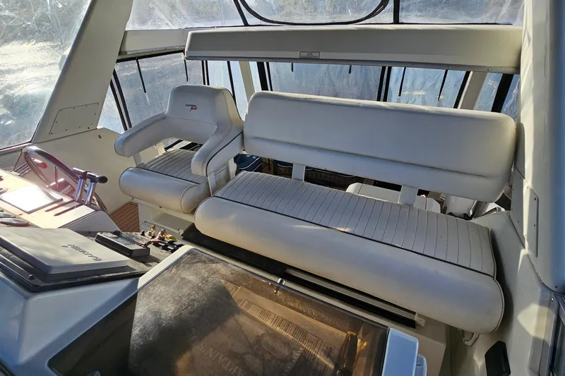 Slide: The Image of 1995 Carver 355 Aft Cabin Motor Yacht helm with white seating and navigation controls. - 13