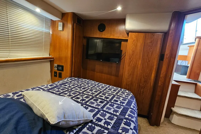 Slide: The Image of 1995 Carver 355 Aft Cabin Motor Yacht interior with bed, TV, and wooden paneling. - 28