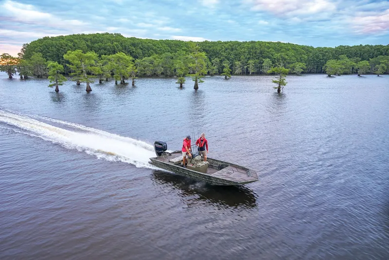 Slide: The Image of Manufacturer Provided Image: 2026 Tracker Grizzly 1860 CC boat cruising on a serene lake with lush green trees. - 43