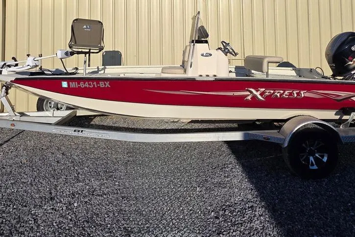 Slide: The Image of 2016 Xpress H20B Bay boat on trailer, red and white design, parked outside. - 7