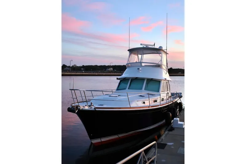 Slide: The Image of 2018 Sabre 48 Flybridge Sedan yacht docked at sunset with pink sky. - 1