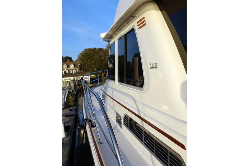 Slide: The Image of 2018 Sabre 48 Flybridge Sedan yacht docked, showcasing sleek design and polished railings. - 4