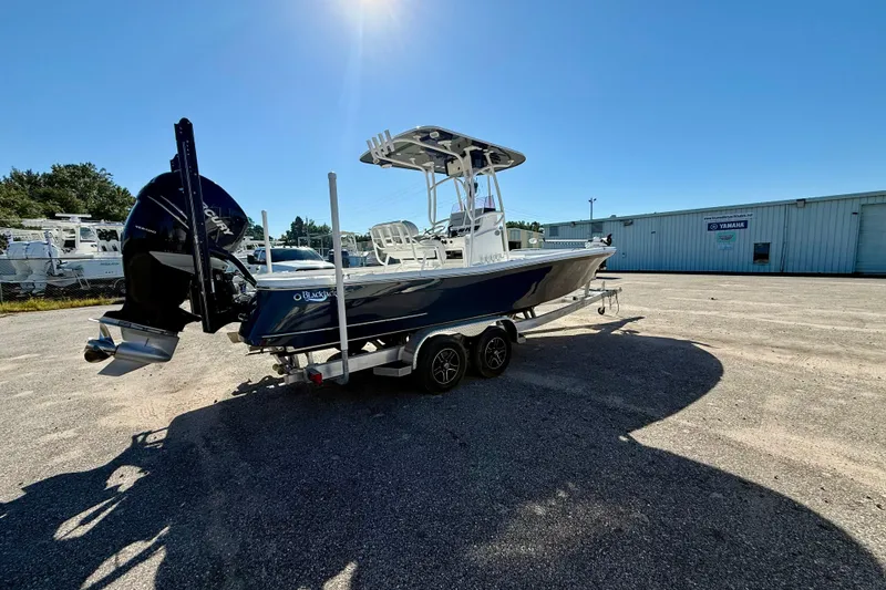 Slide: The Image of 2021 BlackJack 256 Bay boat on trailer, parked outdoors under clear blue sky. - 9