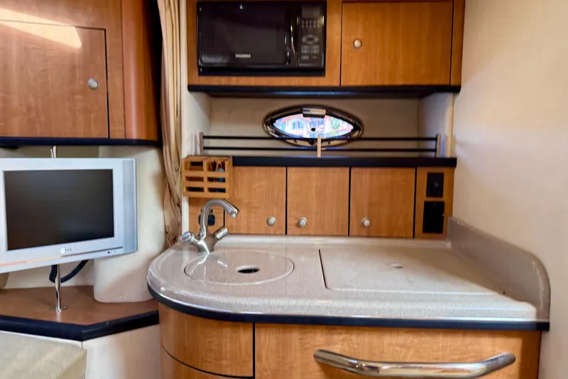 Slide: The Image of 2006 Sea Ray 290 Sundancer interior kitchen with sink, microwave, and TV. - 14
