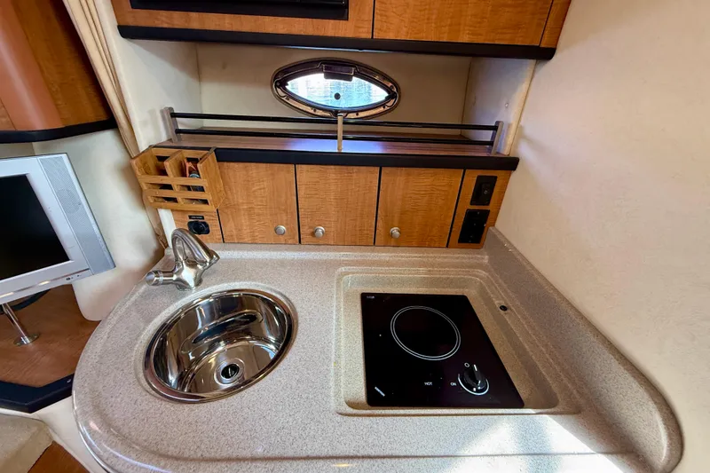 Slide: The Image of Compact kitchen area in a 2006 Sea Ray 290 Sundancer boat with sink and stove. - 15