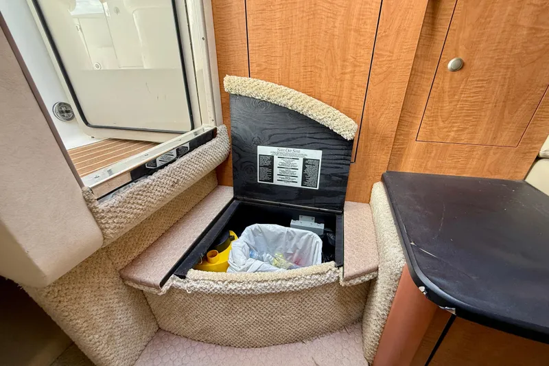 Slide: The Image of 2006 Sea Ray 290 Sundancer interior storage compartment with open lid, revealing trash bin. - 16