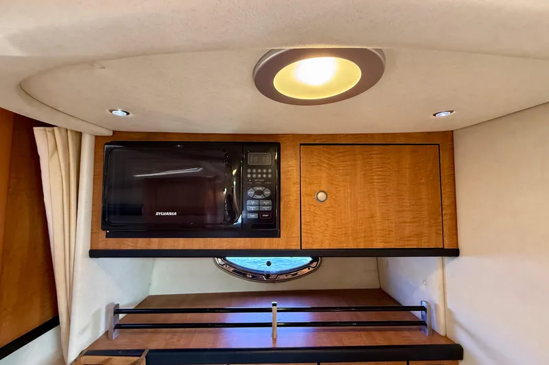 Slide: The Image of 2006 Sea Ray 290 Sundancer interior with microwave and wooden cabinetry. - 17