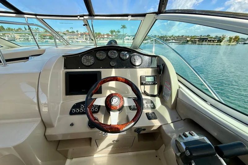 Slide: The Image of 2006 Sea Ray 290 Sundancer helm with wood-accented steering wheel and modern controls. - 27