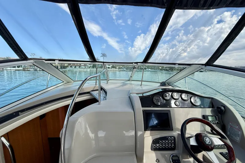 Slide: The Image of 2006 Sea Ray 290 Sundancer cockpit with steering wheel, gauges, and waterfront view. - 29