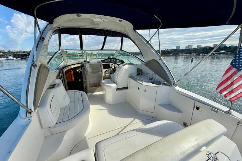 Slide: The Image of 2006 Sea Ray 290 Sundancer boat interior with seating, helm, and American flag on calm water. - 32