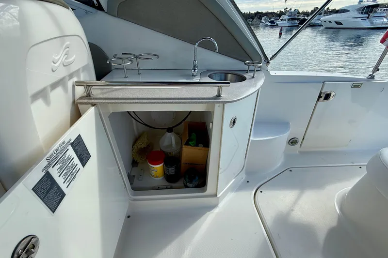Slide: The Image of 2006 Sea Ray 290 Sundancer boat interior with open cabinet and sink area. - 34